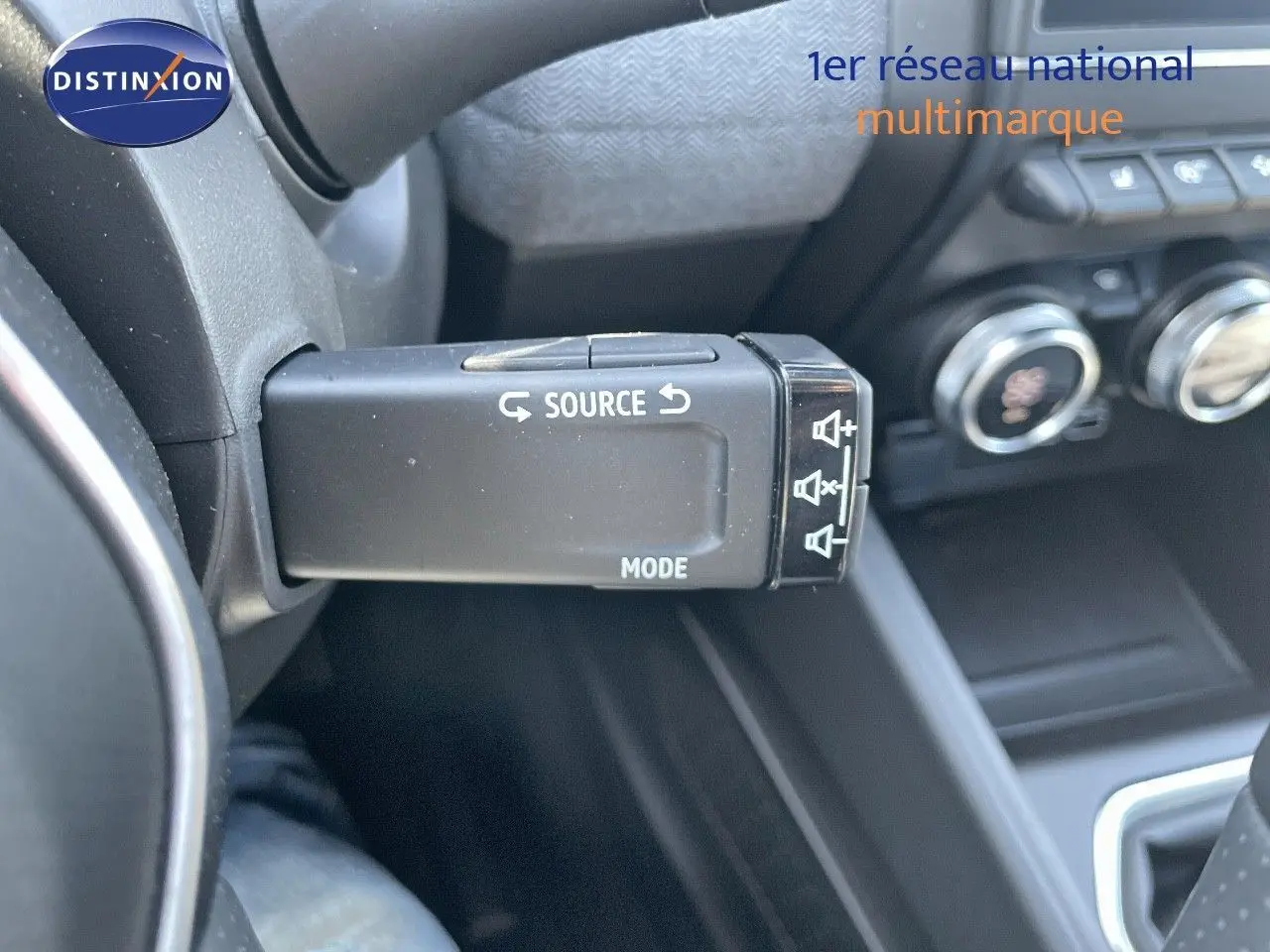 Gros plan sur la commande au volant de la Renault Clio TCE 90CH TECHNO 2025, intérieur noir avec boutons de source et mode.