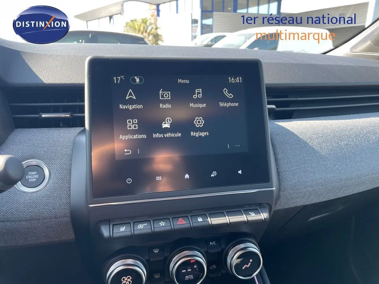 Vue rapprochée du tableau de bord de la Renault Clio 2025, écran tactile central avec commandes climatisation et bouton start noir.