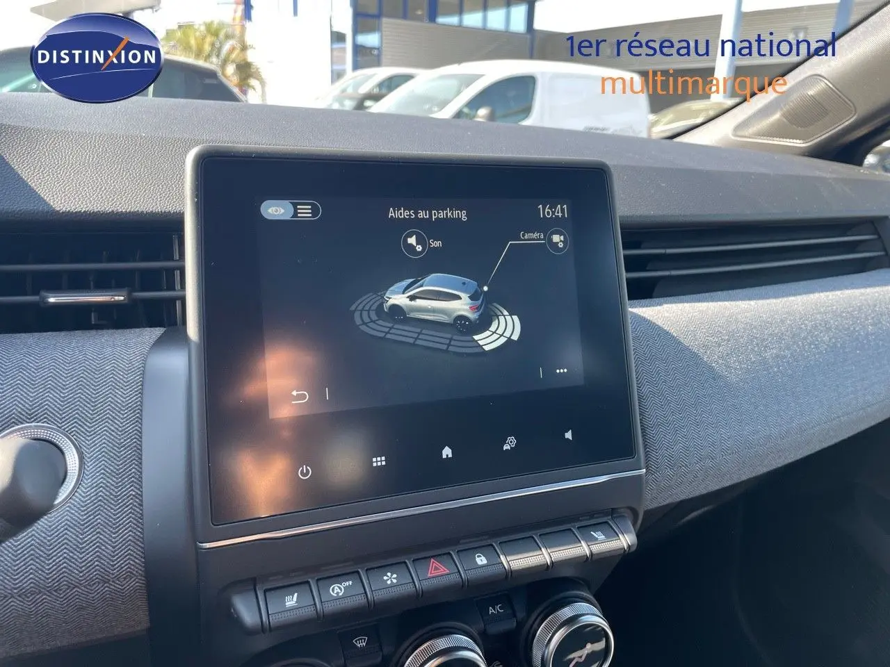Écran tactile central affichant l'aide au parking dans l'habitacle d'une Renault Clio noir métal, vue de face.