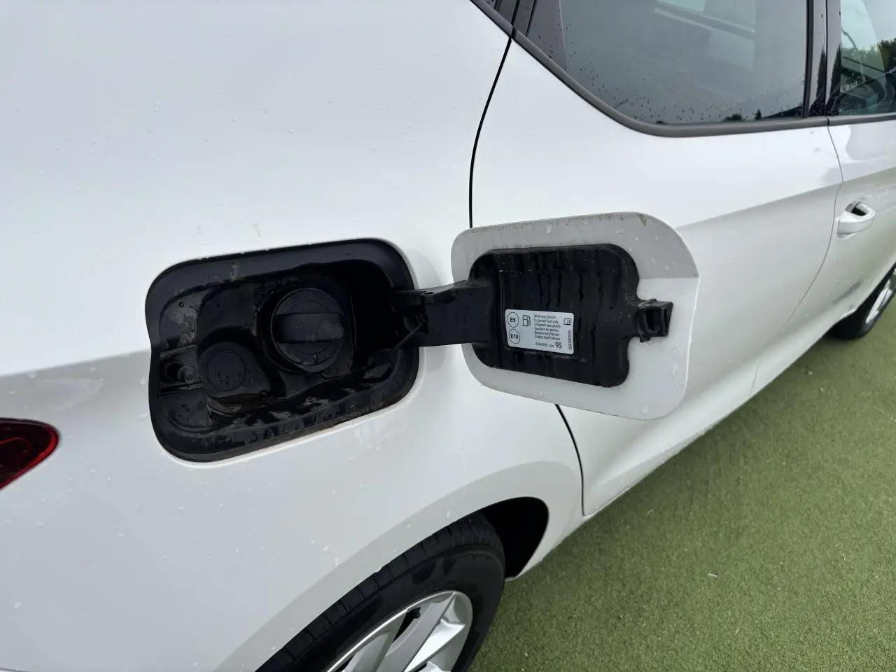 Vue latérale droite du réservoir ouvert d'une SEAT LEON blanche 2024 avec jante alliage 16 pouces visible sur sol vert.