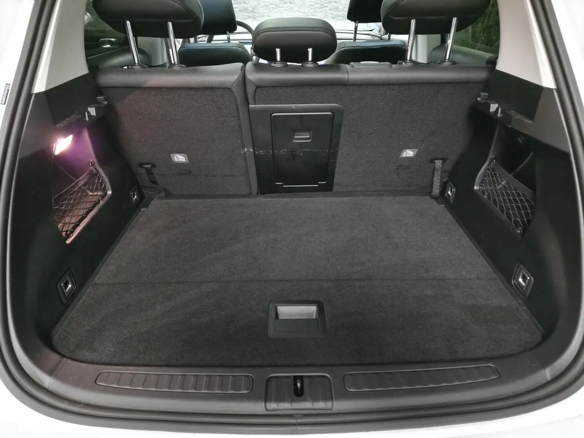 Coffre ouvert vu de l'arrière d'une Smart #1 blanche, avec banquette arrière noire et filet de rangement latéral.