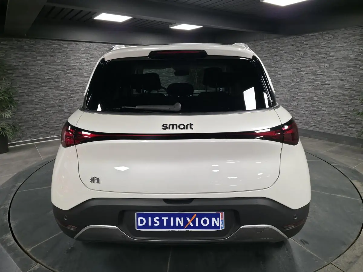 Vue arrière d'une Smart #1 électrique blanche avec feux arrière reliés par une bande lumineuse rouge.