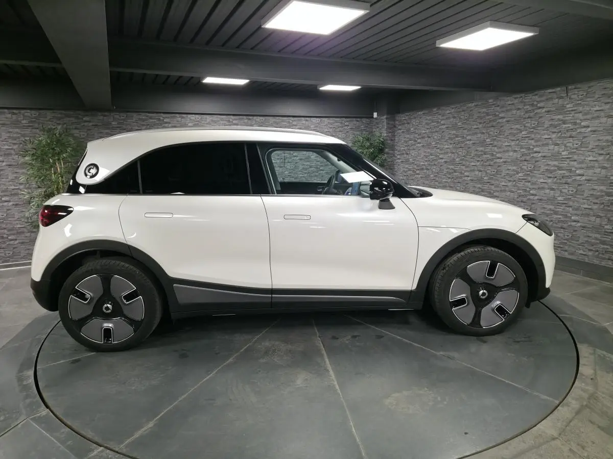 Vue latérale droite d'une Smart #1 blanche électrique 2024 avec jantes modernes et toit blanc contrasté.