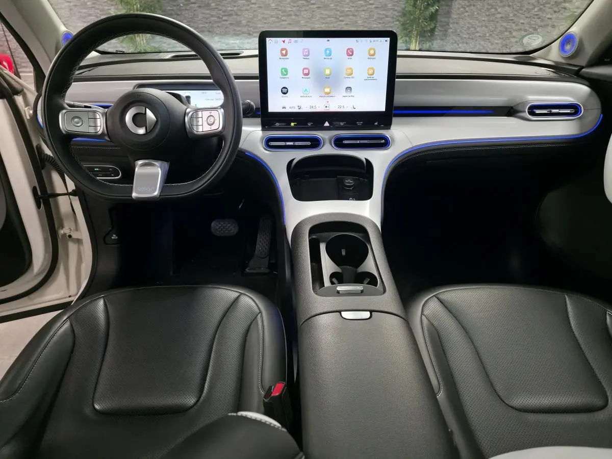 Intérieur avant du Smart #1 2024 blanc, tableau de bord moderne avec écran tactile central et éclairage d'ambiance bleu.