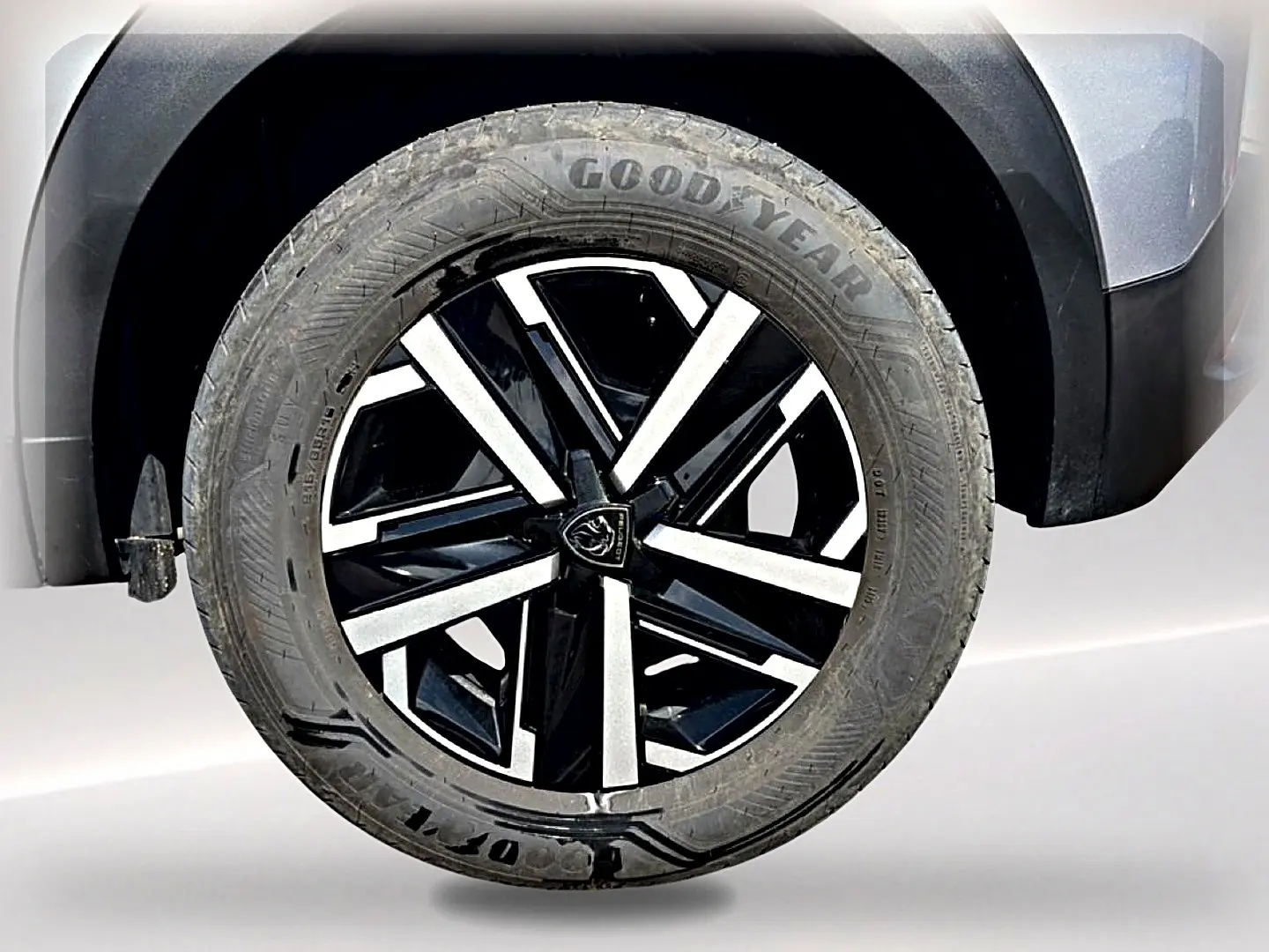 Gros plan sur la roue avant droite du Peugeot 2008 gris, avec jante noire et argentée au design moderne.