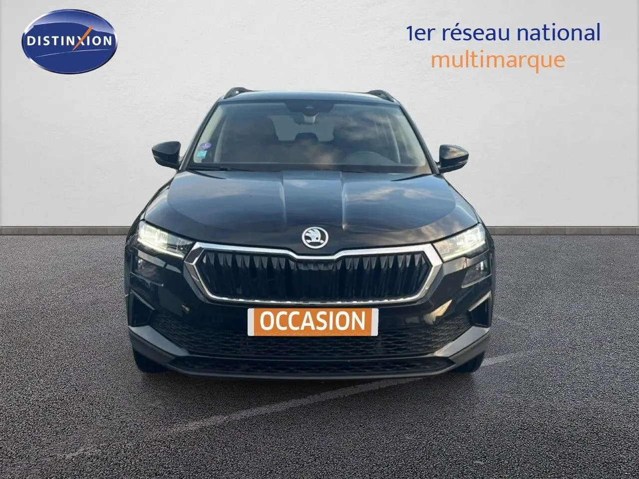 Vue frontale d'un Skoda Karoq noir Magic Metal avec calandre chromée et phares LED allumés sur fond neutre.