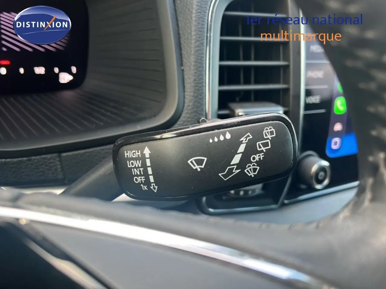 Gros plan sur la commande d'essuie-glace du Skoda Karoq noir Magic Metal, avec tableau de bord et écran tactile en arrière-plan.