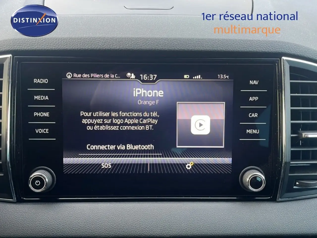 Écran central tactile du tableau de bord d'une Skoda Karoq 2023 avec interface Apple CarPlay et commandes latérales.