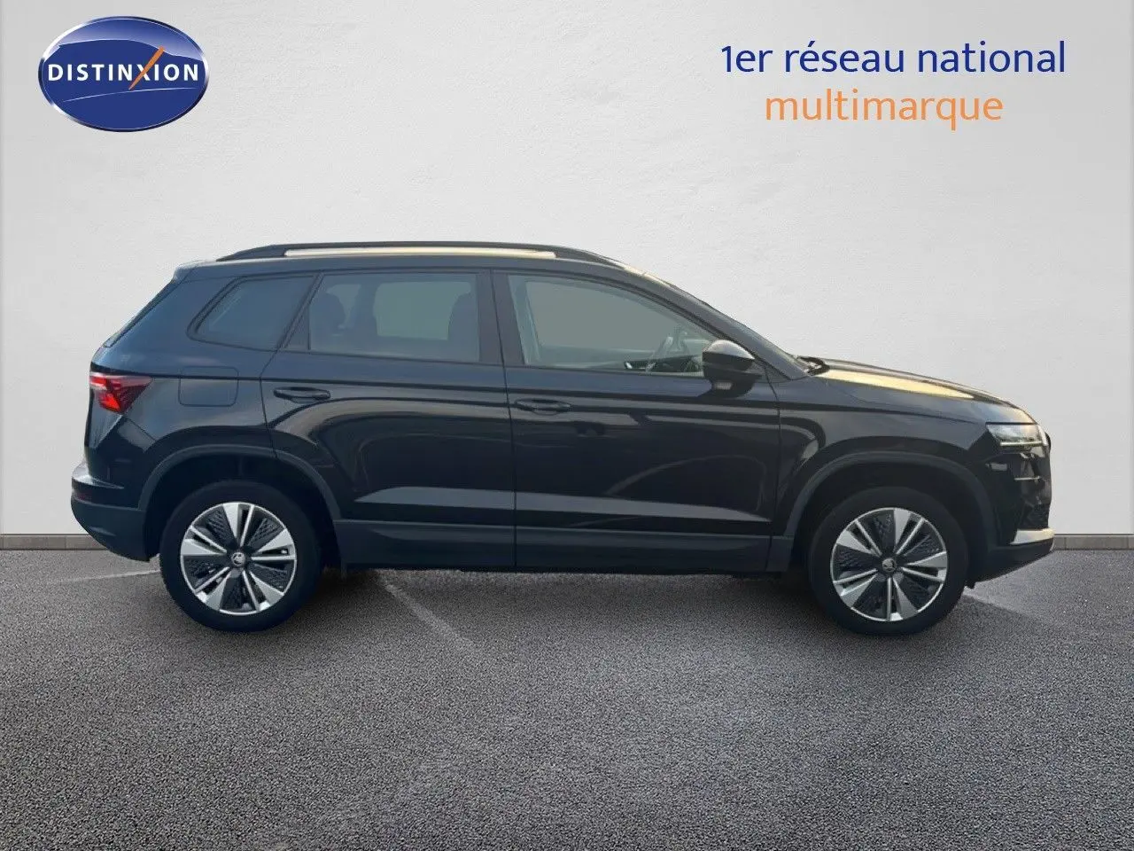 Profil côté gauche d'un SUV SKODA KAROQ noir Magic Metal 2023, avec jantes bi-ton et toit ouvrant visible.