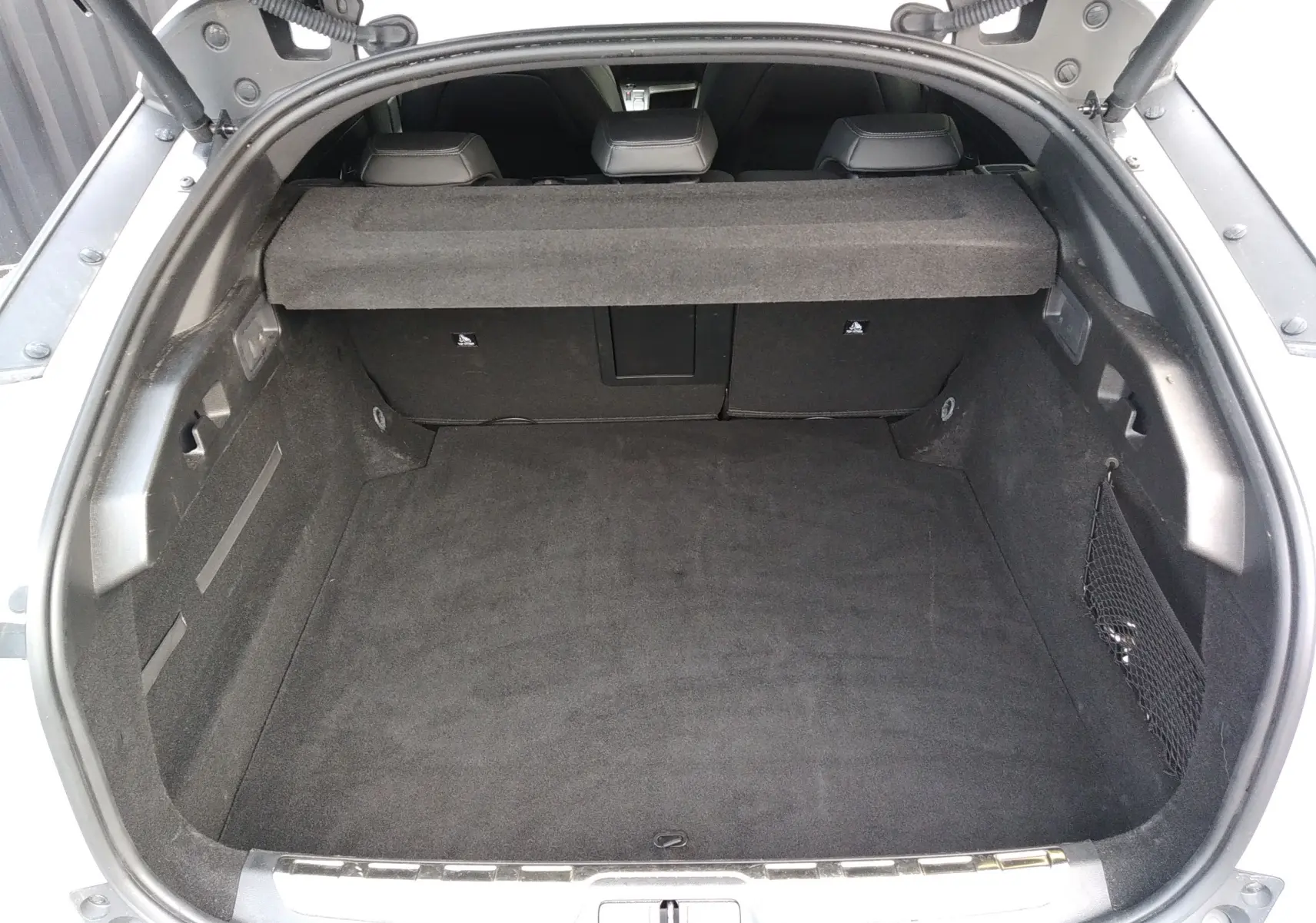 Vue plongeante sur le coffre spacieux et noir de la Peugeot 408 Hybrid 136ch GT blanc Okenite, banquette arrière visible.