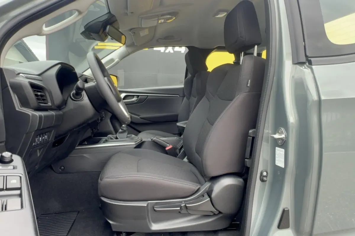 Vue intérieure côté conducteur du pick-up Isuzu D-MAX 2.2 TD vert Inishmore, sièges tissu noirs et tableau de bord visible.
