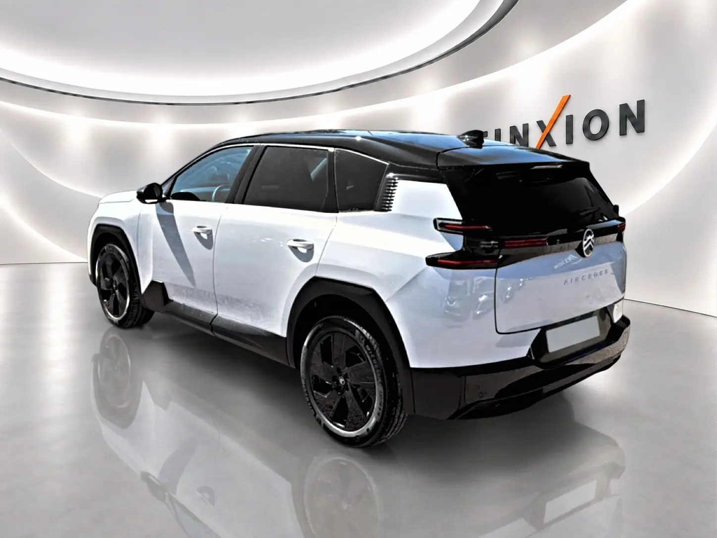 Vue 3/4 arrière droite du Citroën C5 Aircross blanc à toit noir avec jantes alliage noires dans un showroom.