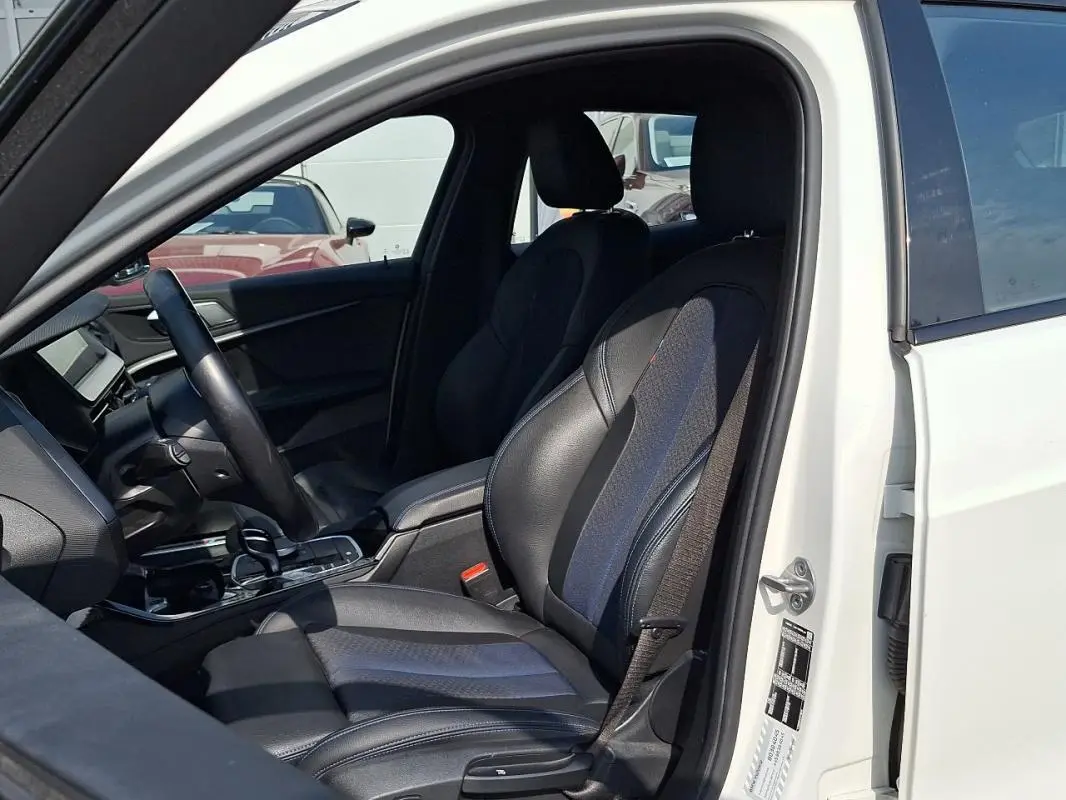 Intérieur côté conducteur d'une BMW Série 1 blanche 120i M Sport 2021, sièges sport cuir noir et bleu.