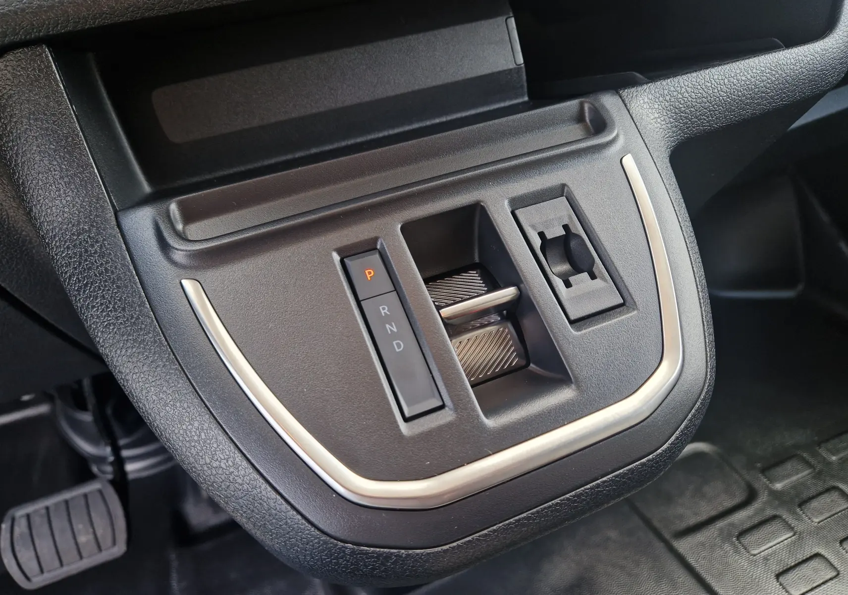 Gros plan sur la console centrale du Citroën Jumpy XL gris titane, montrant la commande de boîte auto et prise 12V.