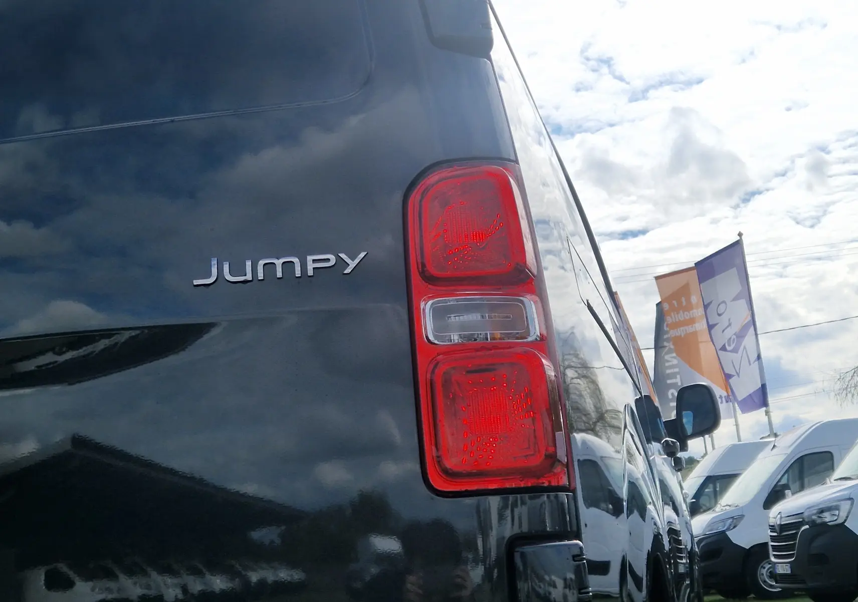 Vue arrière côté droit du Citroën Jumpy gris titane, mettant en valeur le feu arrière et le logo du modèle.