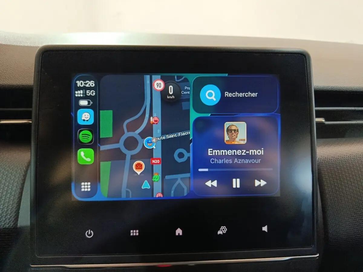 Écran tactile central de la Renault Clio gris clair 2023 affichant navigation et musique en cours.