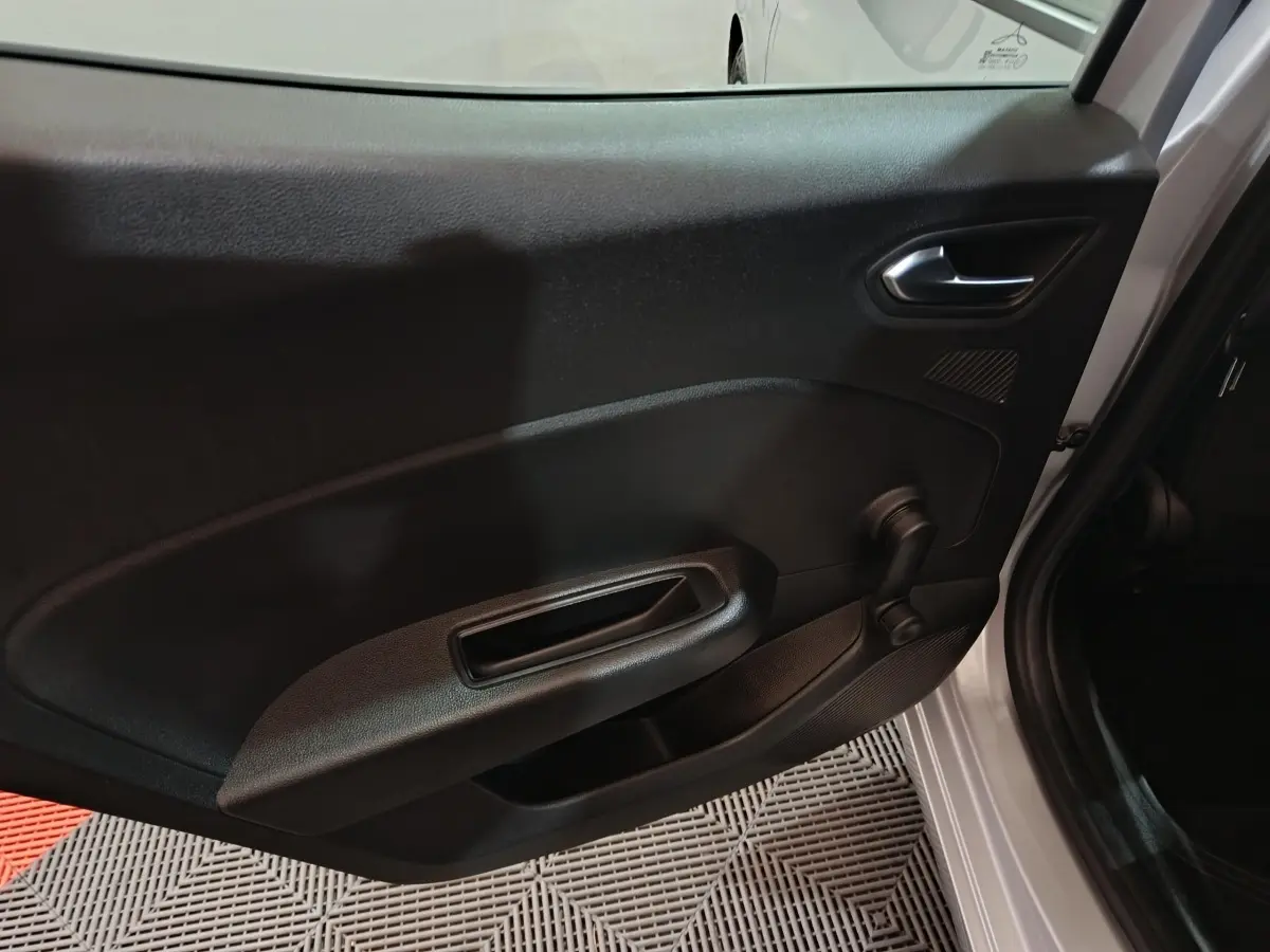 Vue intérieure de la porte avant droite d’une Renault Clio gris clair avec poignée et lève-vitre manuel noir.