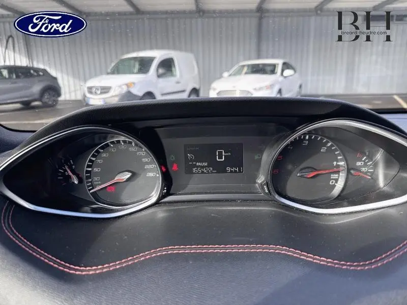 Vue rapprochée du tableau de bord d’un Peugeot 308 SW gris Artense, affichant le compteur et l’écran multifonction.