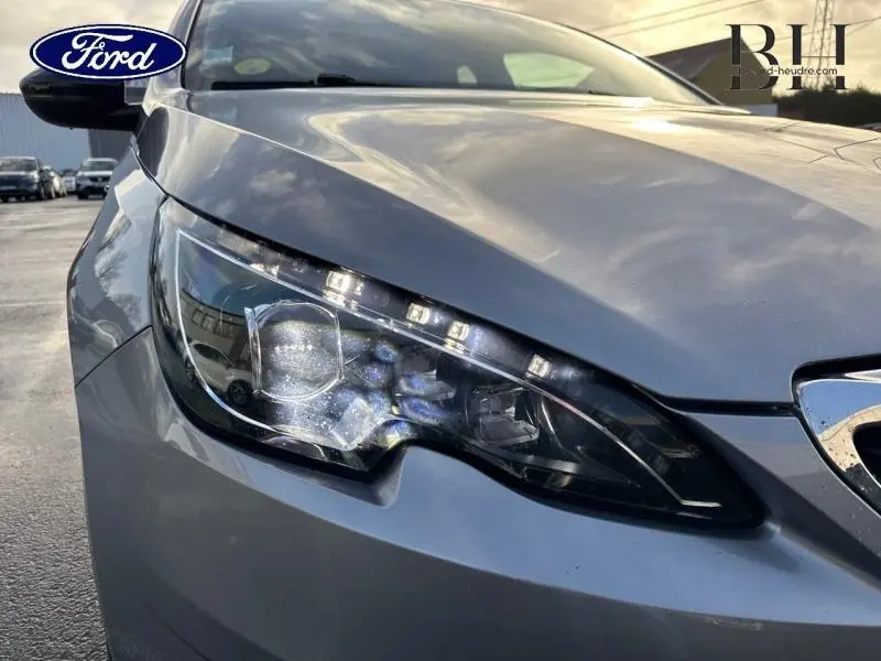 Gros plan sur le phare avant gauche gris Artense du Peugeot 308 SW 2017 avec détails LED et carrosserie lisse.