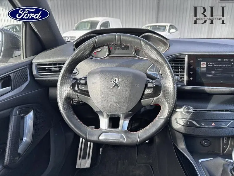 Vue intérieure centrée sur le volant cuir perforé de la Peugeot 308 SW gris Artense avec tableau de bord et écran tactile.