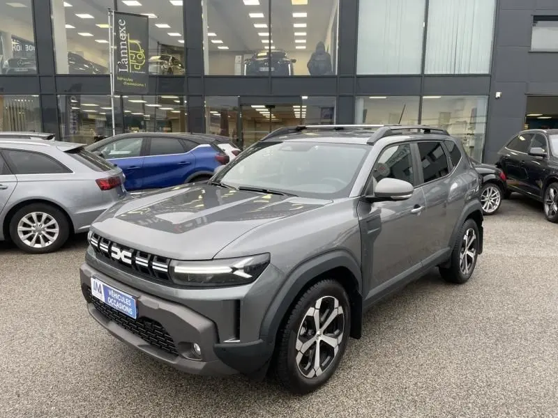 Dacia Duster 1.6 Hybrid 140 cv Journey gris schiste en 3/4 avant droit, avec jantes alliage et toit ouvrant.
