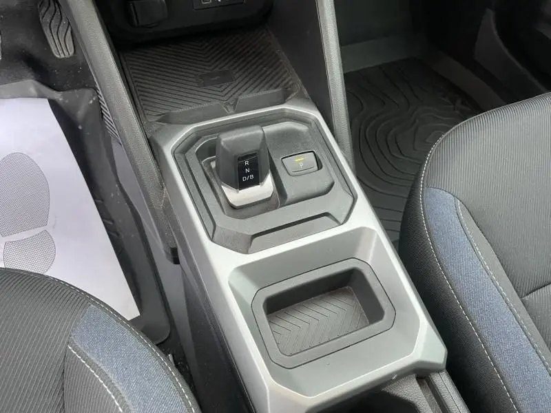 Vue rapprochée de la console centrale grise du Dacia Duster 1.6 Hybrid 2025 avec levier de boîte auto et bouton de parking.