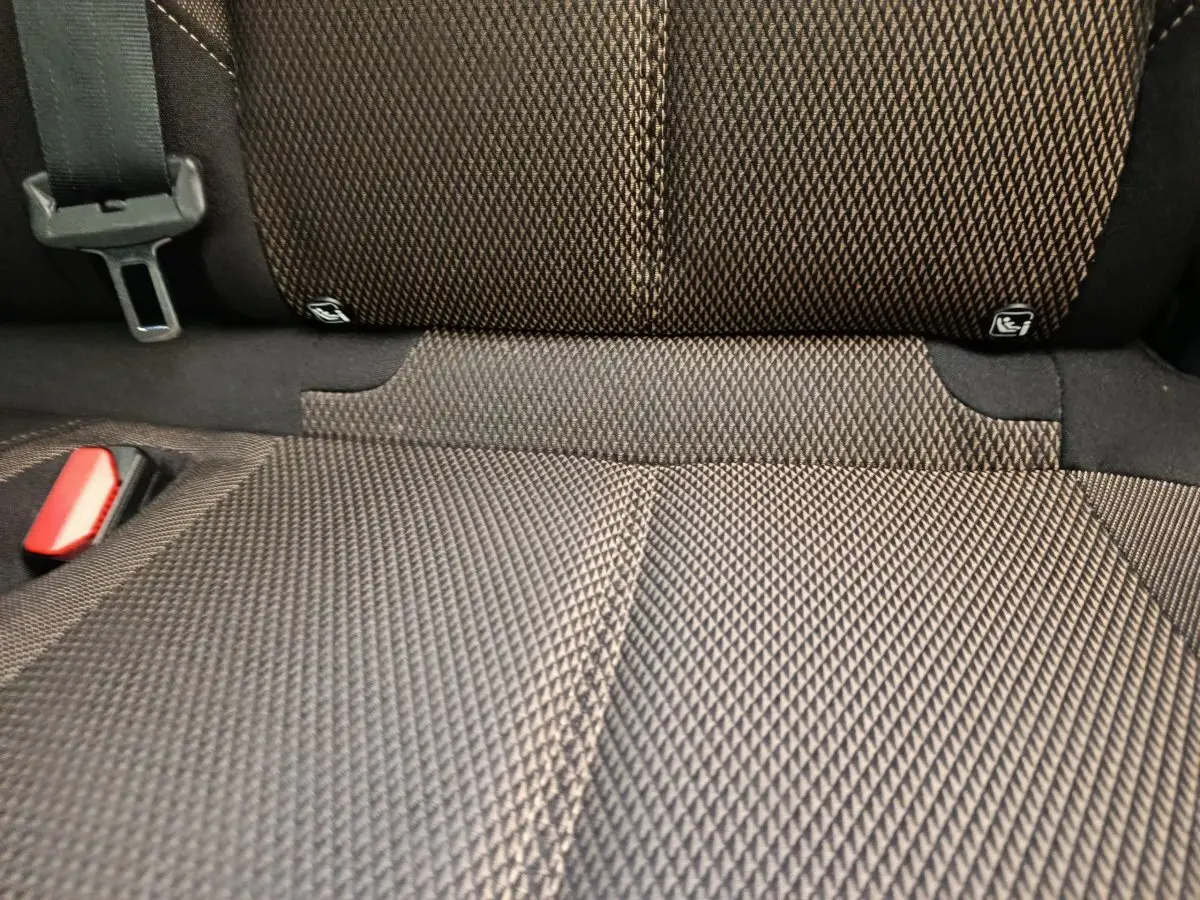 Gros plan sur la banquette arrière en tissu gris foncé avec ceinture de sécurité et fixation Isofix visible.