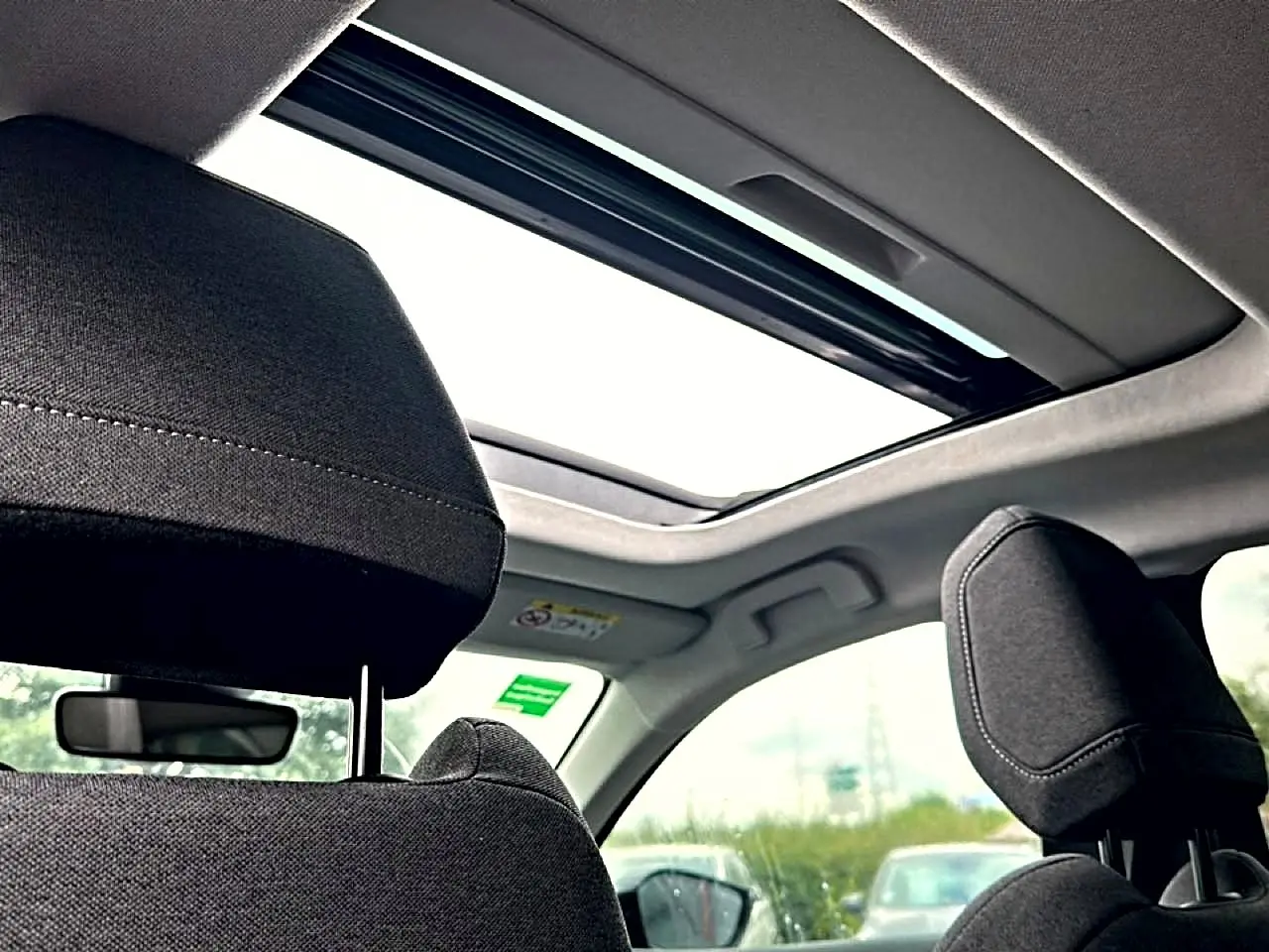 Vue intérieure du toit ouvrant panoramique et des appuie-têtes avant en tissu gris foncé du Citroën C4 2024.
