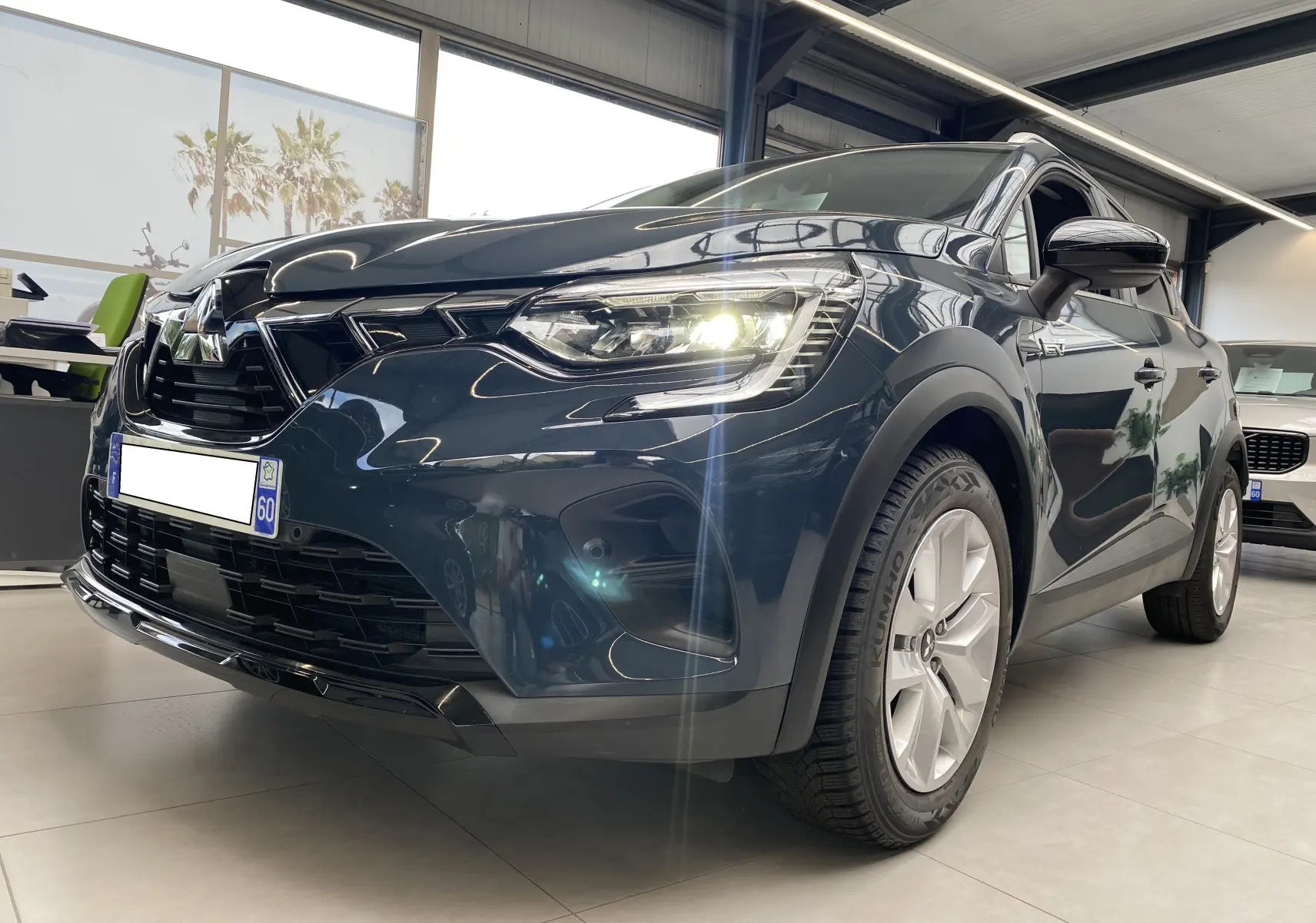 Vue 3/4 avant droit du Mitsubishi ASX 2023 Steel Gray métallisé avec phares allumés en showroom.