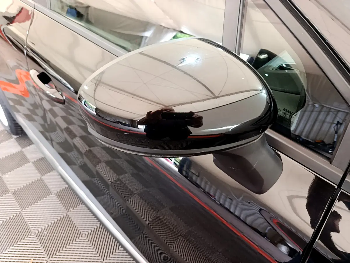 Rétroviseur côté gauche noir brillant du Renault Captur Business 2020, reflétant l'intérieur et l'environnement proche.