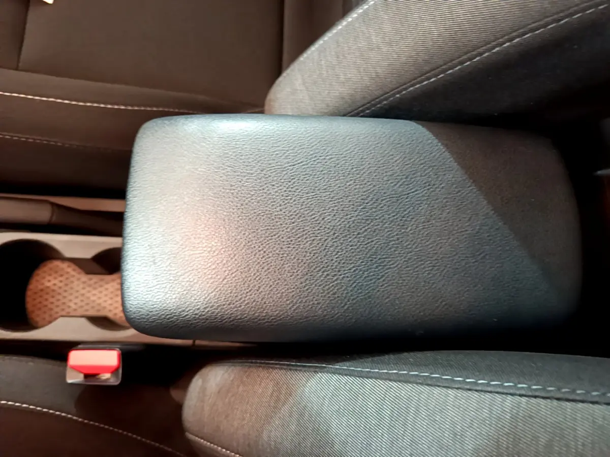 Vue rapprochée de l'accoudoir central noir et des sièges en tissu gris du Renault Captur Business 2020.