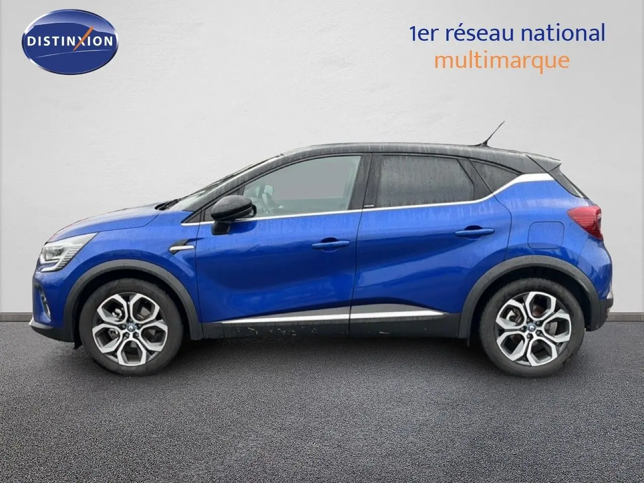 Profil gauche d'un Renault Captur bleu Iron Metal avec toit noir, jantes alliage et lignes blanches contrastantes.