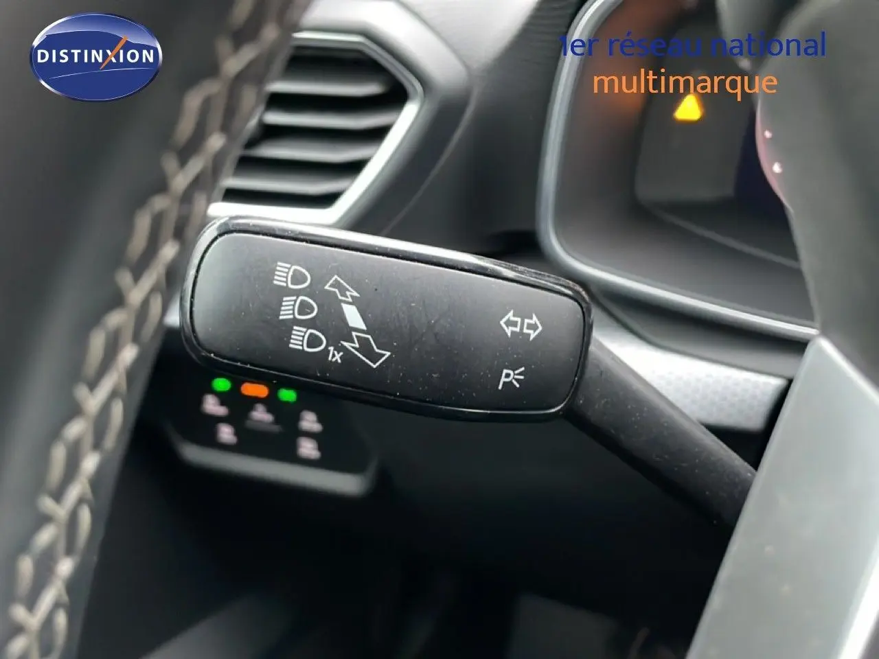 Gros plan sur la commande des clignotants et feux du SEAT LEON ST bleu Fjord, intérieur gris noir visible en arrière-plan.