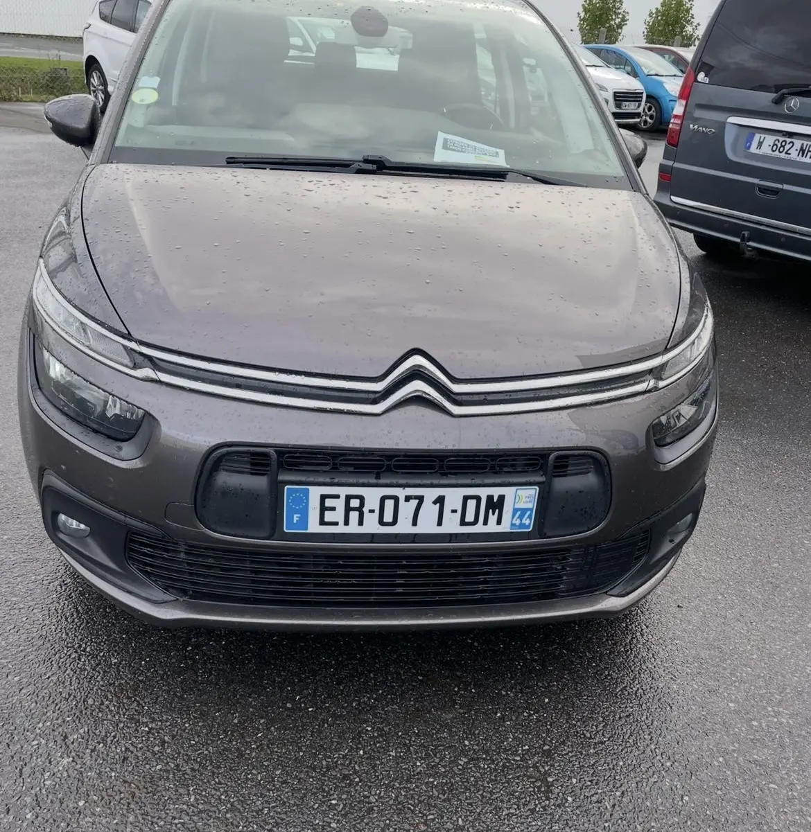 Vue avant d'une Citroën C4 Picasso marron 2017 avec pluie sur la carrosserie et plaques françaises visibles.