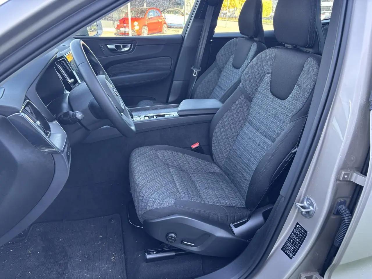 Intérieur avant côté conducteur d’un Volvo XC60 argent crépuscule, sièges tissu à motifs et volant simili-cuir.