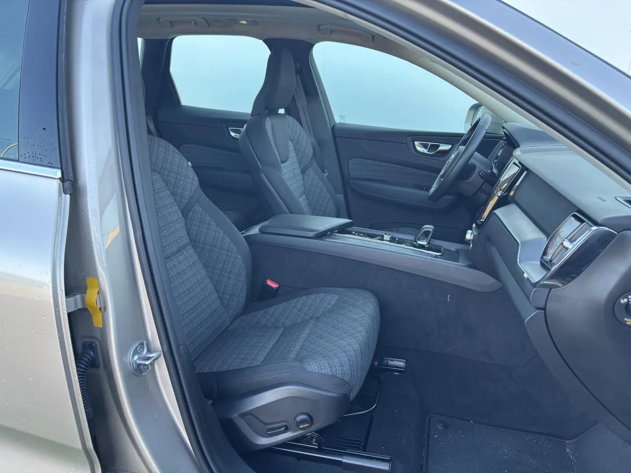 Intérieur côté conducteur du Volvo XC60 2024 argent crépuscule, sièges tissu gris et tableau de bord moderne.