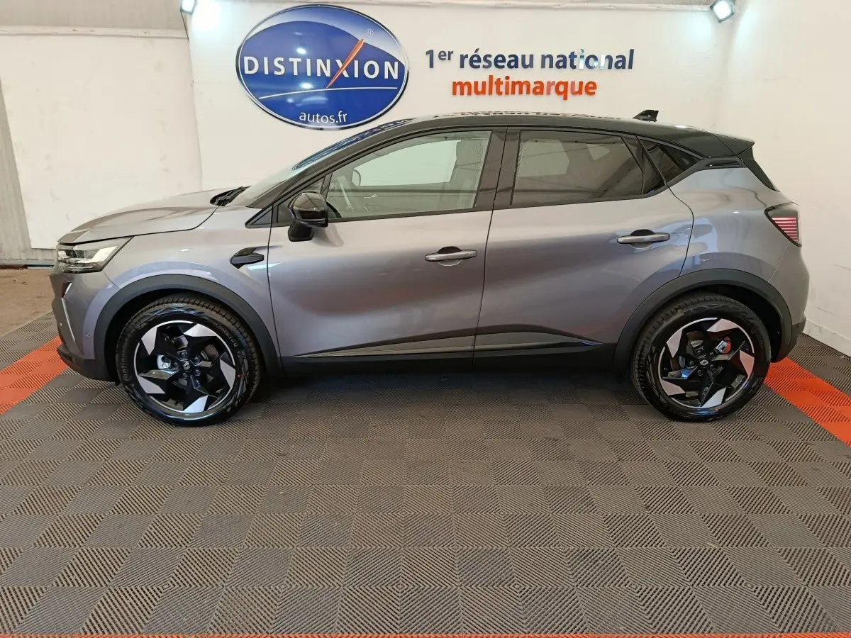 Profil côté gauche du Renault Captur gris foncé 2025 avec jantes noires et logo Distinxion en arrière-plan.