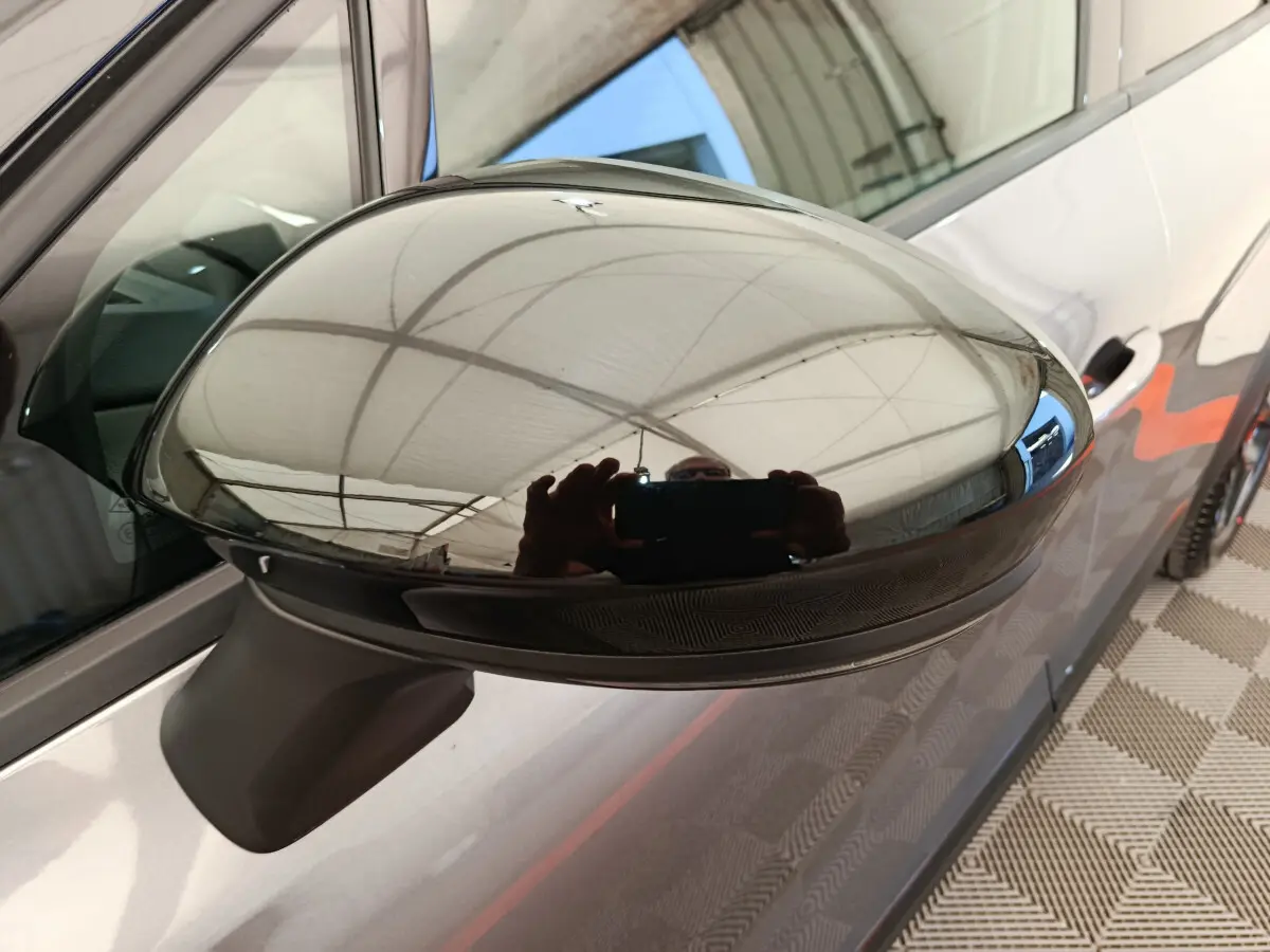 Rétroviseur côté gauche gris foncé du Renault Captur 2025 avec carrosserie et poignée de porte visibles en arrière-plan.