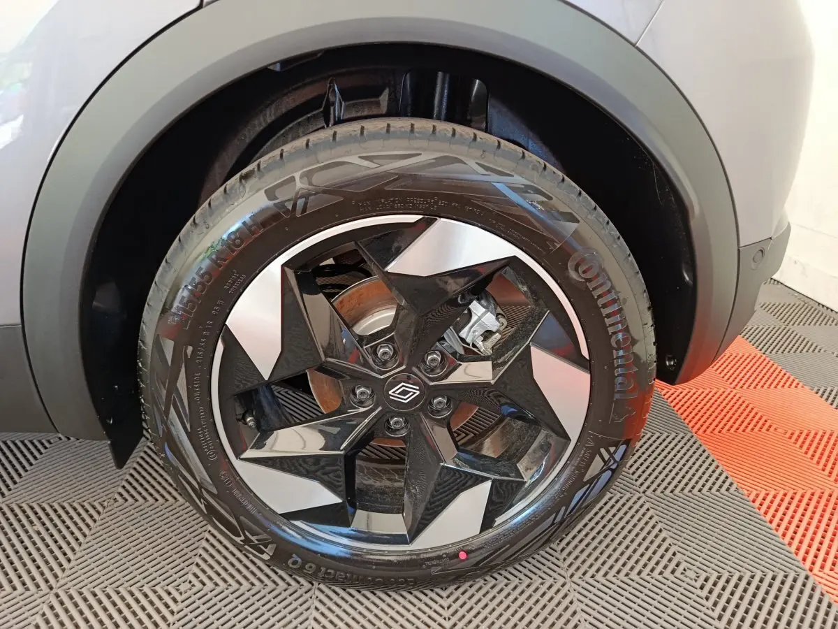 Gros plan sur la roue avant droite du Renault Captur gris foncé, mettant en valeur la jante noire et argentée au design géométrique.