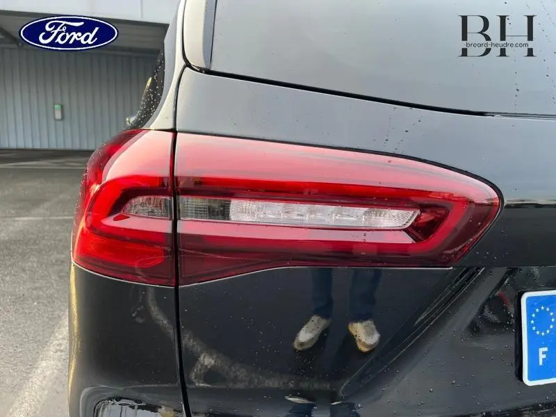 Gros plan sur le feu arrière gauche rouge d’une Ford Focus SW 2024 noir Agate métallisé, avec reflet au bas de la carrosserie.