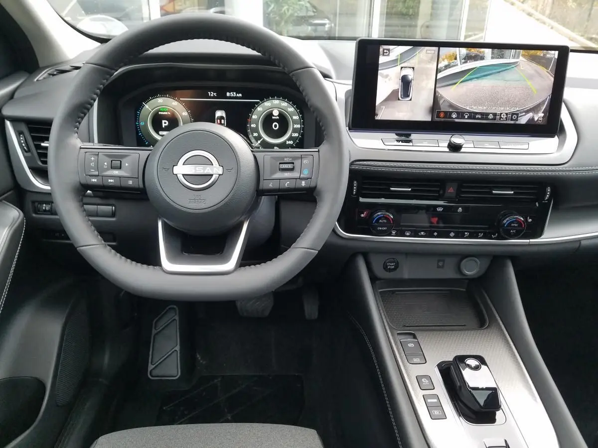 Vue intérieure avant du Nissan Qashqai noir 2025, avec volant multifonction et écran tactile affichant la caméra 360°.