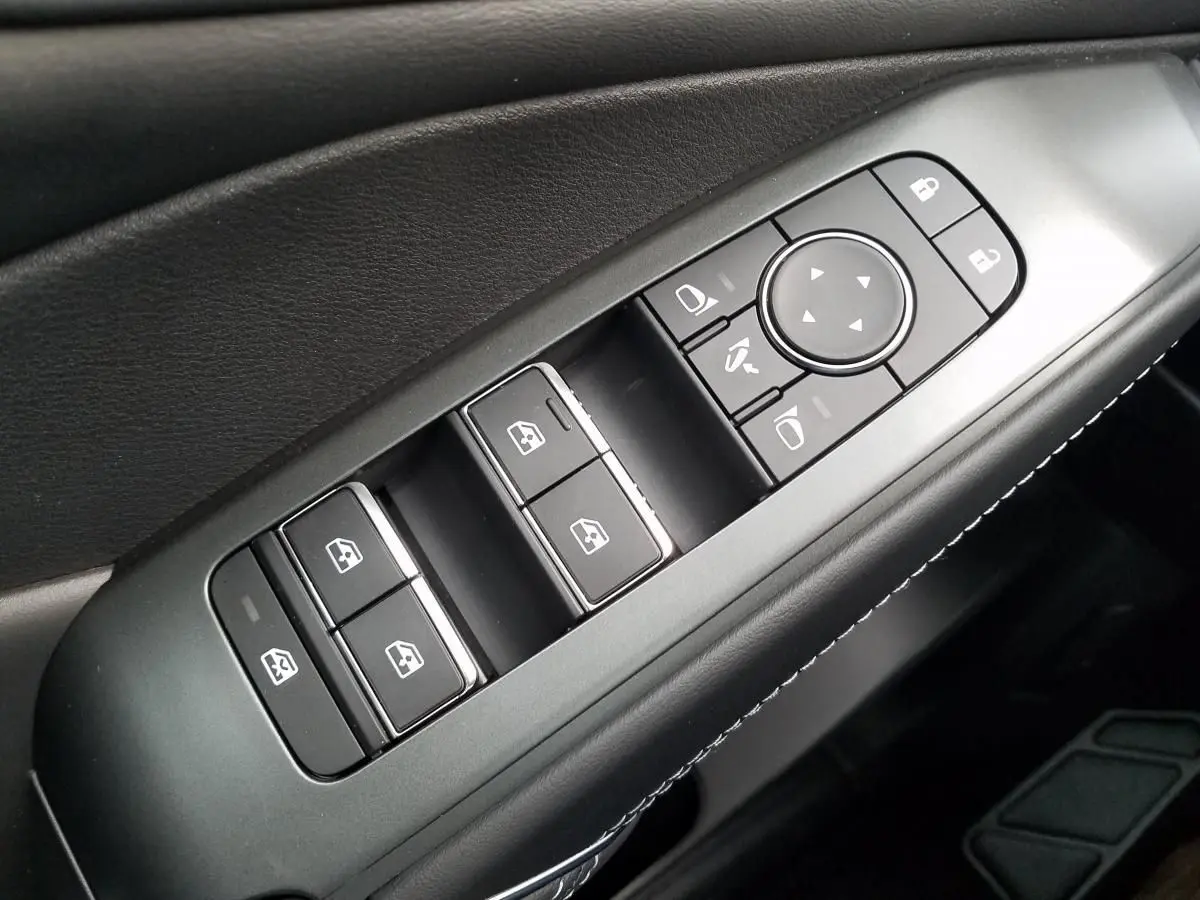 Gros plan sur les commandes de lève-vitres et rétroviseurs côté conducteur du Nissan Qashqai noir 2025.