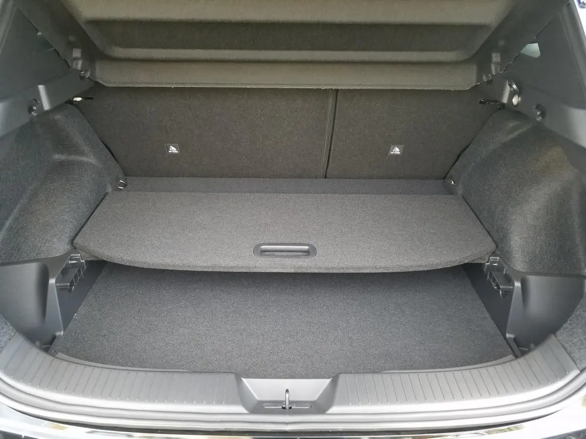 Coffre ouvert vu de l'arrière du Nissan Qashqai noir 2025, montrant la plage arrière et le tapis de coffre.
