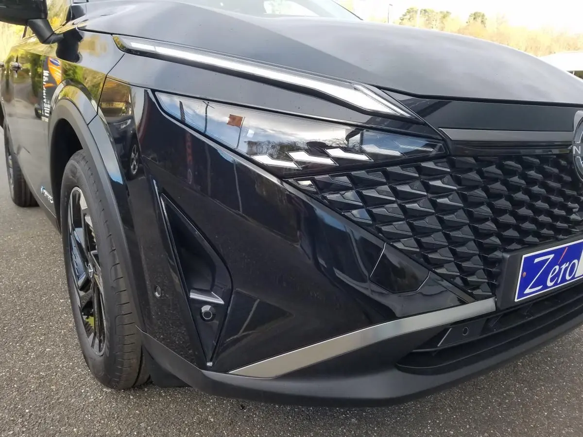 Vue avant gauche rapprochée du Nissan Qashqai noir 2025 avec calandre texturée et phares LED distinctifs.