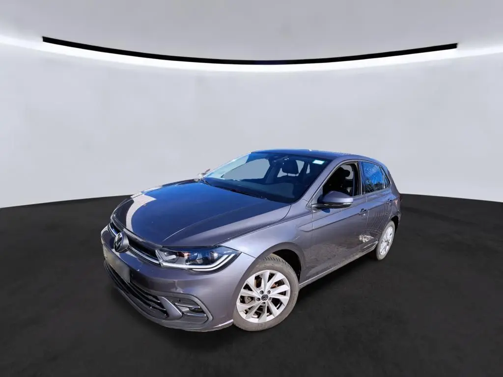 Volkswagen Polo gris 3/4 avant droit, avec projecteurs LED et jantes alliage 16 pouces visibles.