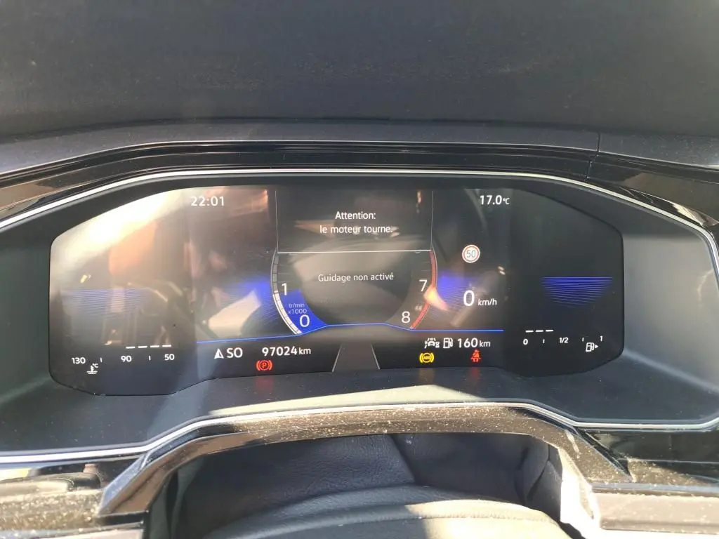 Tableau de bord numérique de Volkswagen Polo gris 2022, affichant vitesse, température et alertes moteur.