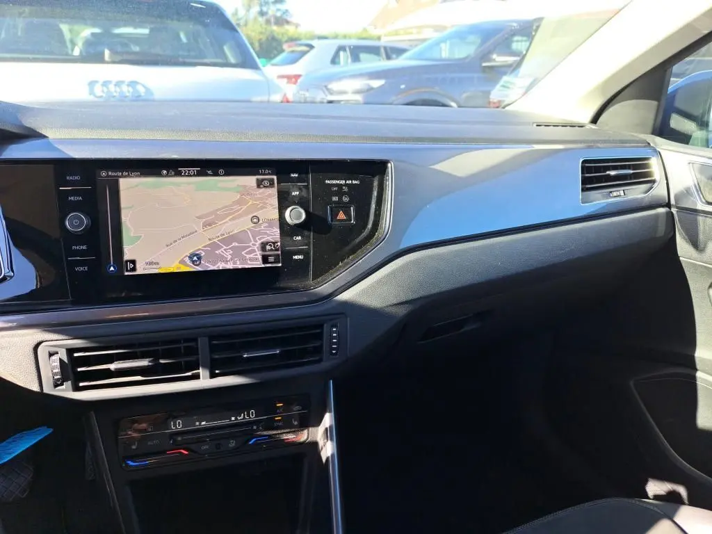 Vue intérieure côté passager du tableau de bord de la Volkswagen Polo gris 2022 avec écran GPS et aérateurs horizontaux.