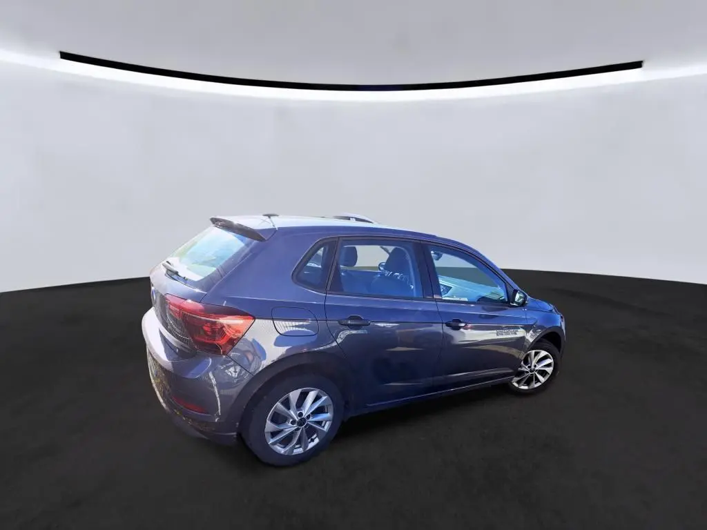 Vue 3/4 arrière droite d'une Volkswagen Polo gris métallisé avec jantes alliage et déflecteur de toit intégré.