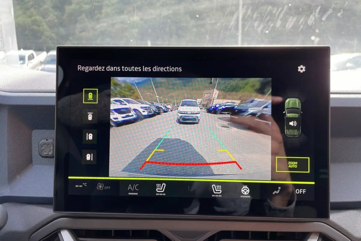 Écran de caméra multiview affichant une vue arrière avec un Dacia Duster vert cèdre en stationnement.