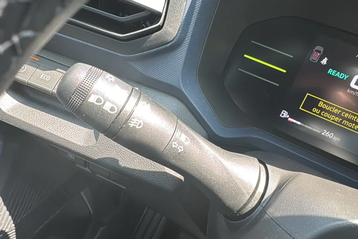 Gros plan sur la commande des feux à gauche du volant du Dacia Duster HEV 140 Journey Plus 2025.